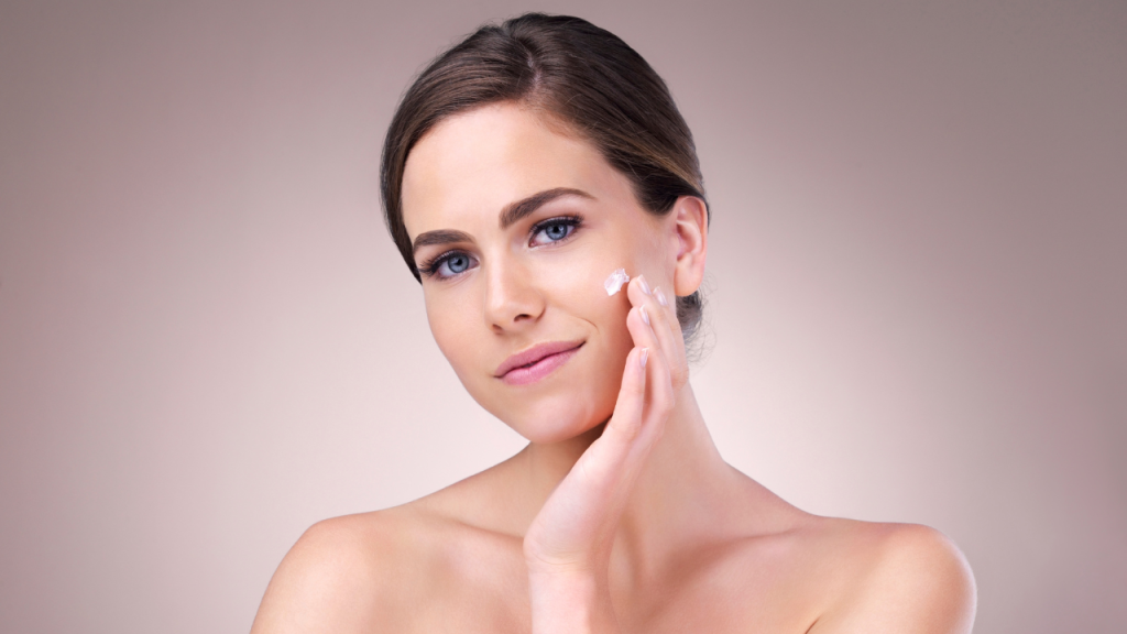 Woman applying moisturizer to her cheek, demonstrating a calming step in a simplified ADHD skincare routine.