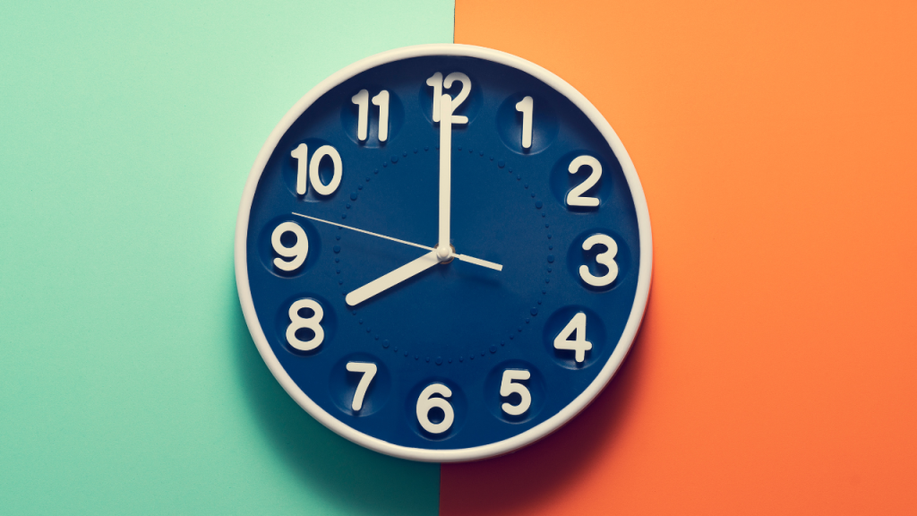 A blue wall clock on a vibrant split-color background, representing the importance of time-based habits and routines in ADHD skincare