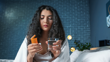 Woman holding a pill and water symbolizing how Ritalin affects skin when mixed with alcohol or substances.