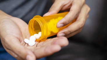 Hands holding white pills from an orange bottle symbolic of how Ritalin affects skin health and daily skincare routines.