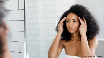 Black woman checking skin in the mirror; a mindful moment in an ADHD skincare routine