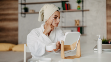 Woman applying skincare cream while looking in a mirror emphasizing how Ritalin affects skin and the need for a consistent routine.